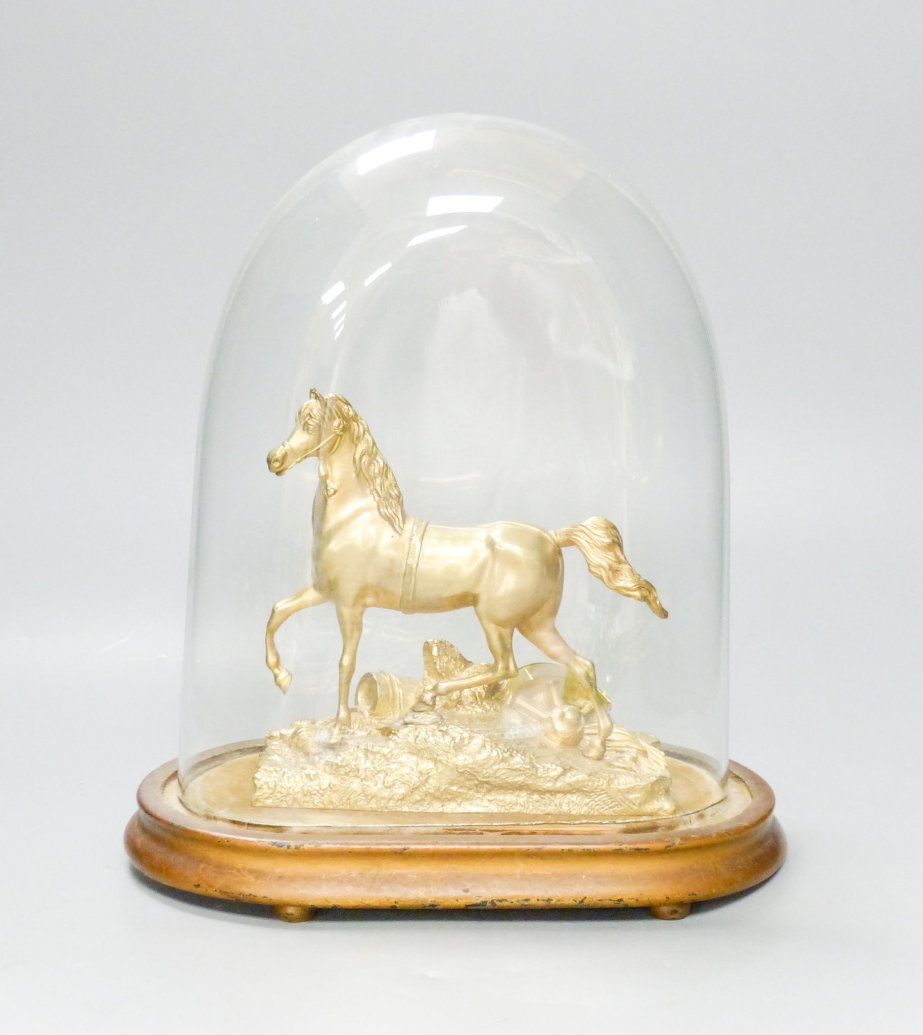 A Victorian gilt metal model of a horse with trophies of war to the base, under a glass dome, total height 30 cm